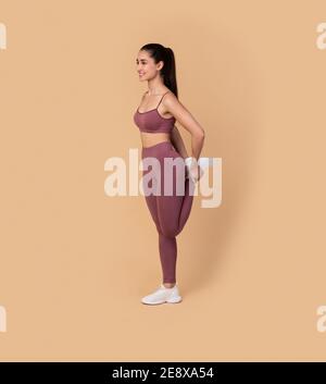 Smiling Young Woman Stretching Leg At Studio Stock Photo