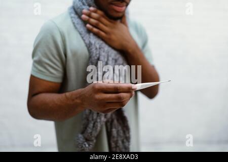 Sick African Man Holding Thermometer Standing On Gray Background, Cropped Stock Photo