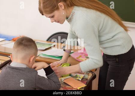 art Teacher Helping Pre School Pupil In Art Class. red haired young teacher and cute little boy drawing. Stock Photo