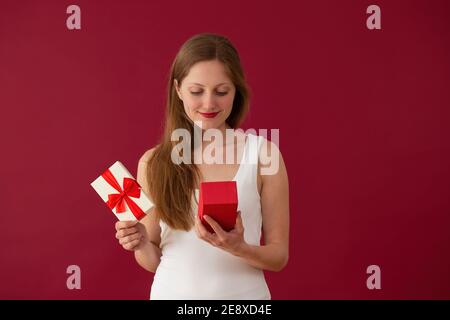 Blonde girl looking to the present on red background Stock Photo