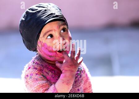 portrait of Kid face full of color while playing with color during holi festival of colors Stock Photo
