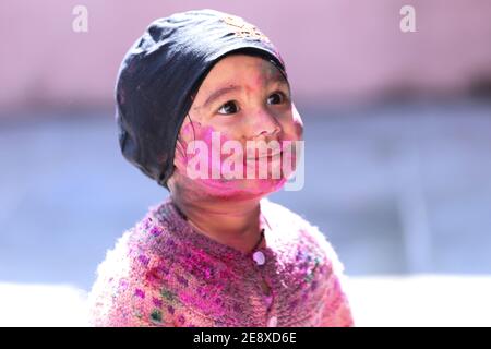 portrait of Kid face full of color while playing with color during holi festival of colors Stock Photo