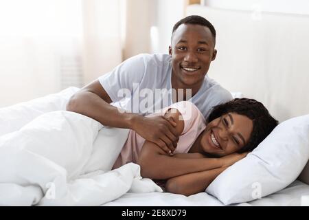 Happy black couple cuddling in bed at home Stock Photo
