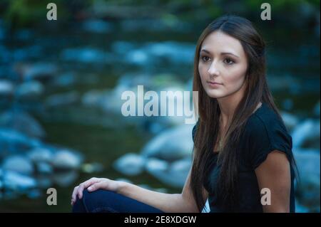 A young woman poses along the banks of a small river. Stock Photo