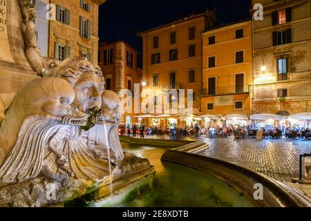 Closeup of the Pantheon Fountain or Fontana del Pantheon in the Piazza della Rotonda at night with sidewalk cafes and shops illuminated in Rome Italy Stock Photo