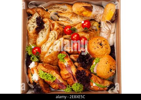 Delivery of food in a box, delicious and fresh food. Convenient boxing for eating at home, at work, in nature. Croissants with ham, burgers, pastries, Stock Photo