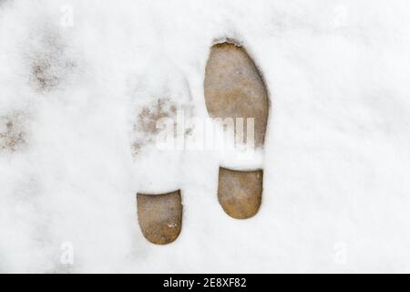 close up of two footprints in snow covered paving slab outside on a cold winters day Stock Photo