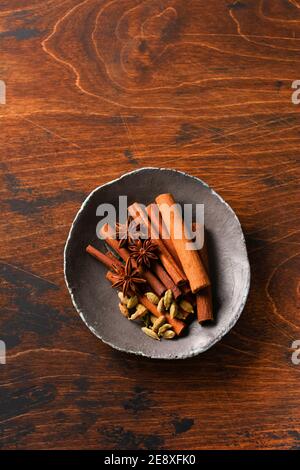 Assorted natural cinnamon sticks, cardamom grains, anise stars baking ingredients on a rustic brown background. Natural spices. Stock Photo