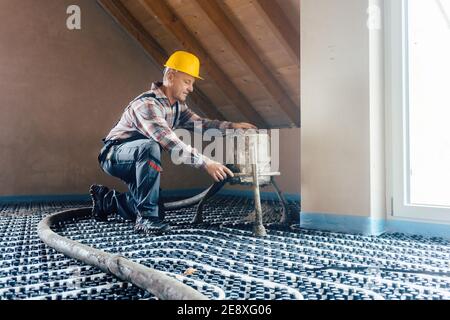 Worker on construction site installing pipes for underfloor heating Stock Photo