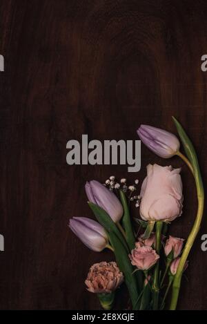 vertical springtime flowers bouquet on brown wood table. elegant pink roses flat lay on rustic wooden table. floral composition as concept as spring s Stock Photo