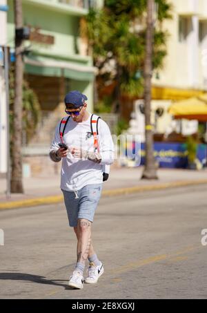 Man walking and looking down at this phone Miami Beach street photography Stock Photo