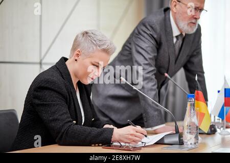 concentrated serious female in suit at conference, listening to talks of partners, at multi-ethnic meeting without ties. business, summit concept Stock Photo
