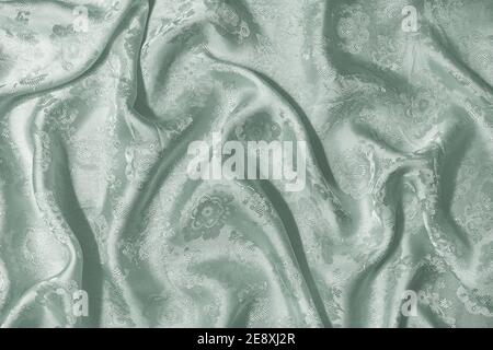 Background with the texture of green silk fabric draped with pleats. Stock Photo