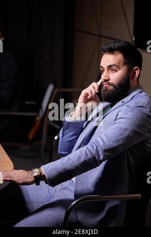 arabic male sits listening to colleagues speech , looking at side, wearing elegant formal suit, discussing startups and finance, at interracial busine Stock Photo