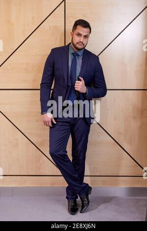 executive in formal wear posing, after meeting with successful people. caucasian male stands looking at camera confidently indoors. success, business, Stock Photo