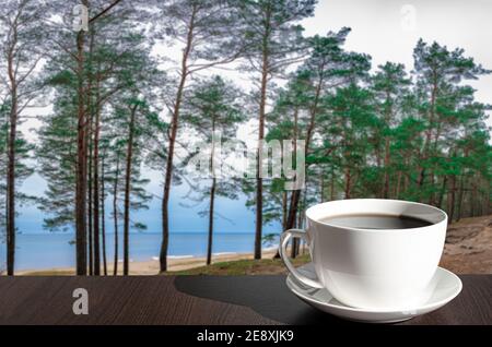 Cup of coffee on the table with view of coniferous forest and blue sea Stock Photo