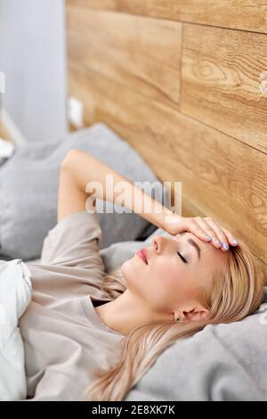 ill woman got fever caught cold lying on bed at home, sick allergic european female having allergy symptoms coughing and having high fever at home, to Stock Photo