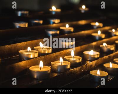 Beautiful, burning, festive candles in the darkness of the old Church Stock Photo