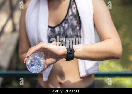 Sportswoman Checking Smart Watch, Young woman jogger ready to run set and looking at sports smart watch, checking performance or heart rate pulse trac Stock Photo