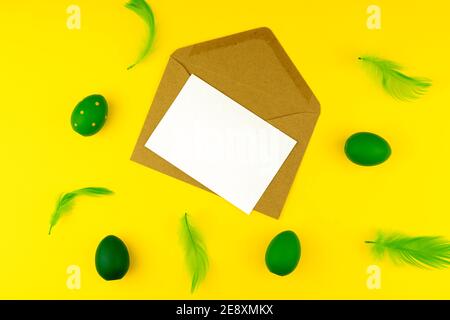Spring Easter layout with green feathers and eggs, craft envelope and blank paper for text Stock Photo