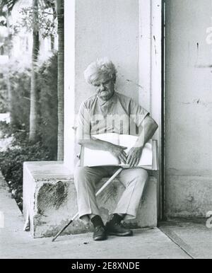 Elderly blind man sitting and reading a large braille book outside an office building in Miami, Florida. Stock Photo