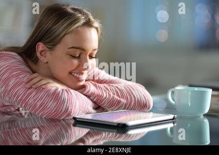 Happy teen watching media on tablet in the night in the living room at home Stock Photo