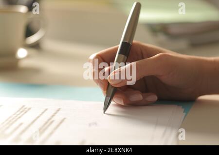 Profile close up of a woman hand singing paper contract at office