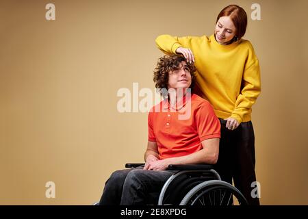 disabled man enjoying time his beautiful kind girlfriend taking care of him touching his hair. isolated background Stock Photo