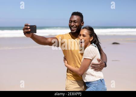 African american couple taking a selfie with smartphone on a beach by the sea Stock Photo