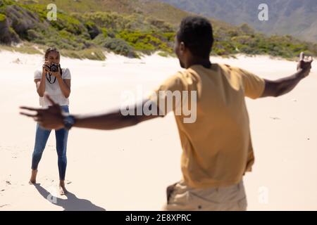 African american couple taking photos with camera on a beach by the sea Stock Photo