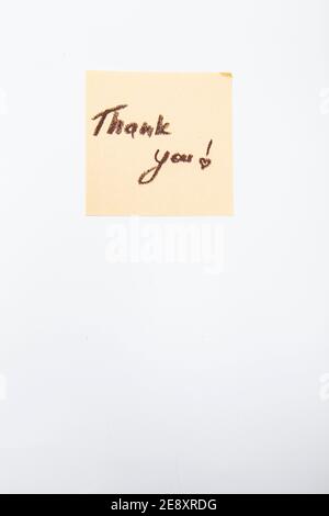 Vertical shot of a thank you note handwrtitten on yellow sticky paper Stock Photo