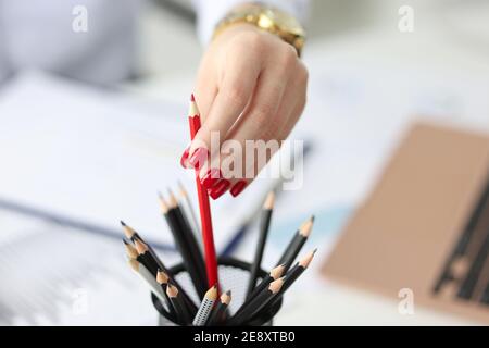 Female hand with red manicure pulling out pencil in office closeup Stock Photo