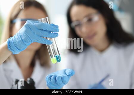 Women scientists holding test tubes with liquid in laboratory Stock Photo