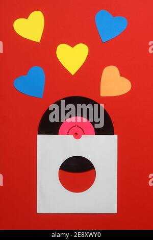 Aged White paper cover and vinyl LP record isolated on Red background. 45rpm Vinyl Record with Sleeve. Stock Photo