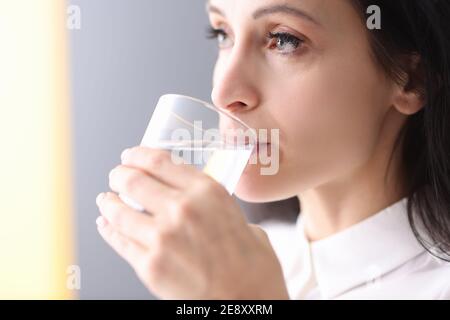 Young woman holding glass in her hands and drinking water from it Stock Photo