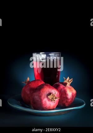 Pomegranate fruit on a plate with a glass of pomegranate juice, close up. Stock Photo