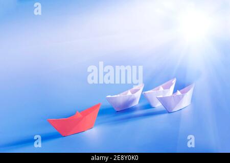 Group of origami boats on blue background. Red paper ship leading. Leadership, Business for innovative solution concept Stock Photo