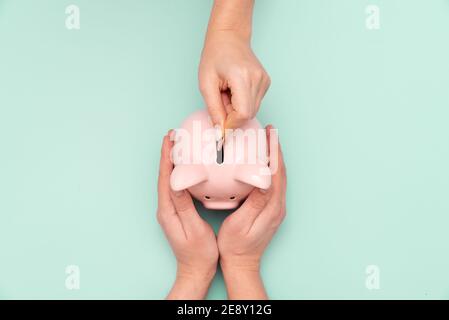 Woman puts a coin in a piggy bank. Budget, money savings concept Stock Photo