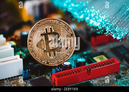 Bitcoin cryptocurrency, virtual money, blockchain technology concept. Golden coin on electronic mainboard. Stock Photo