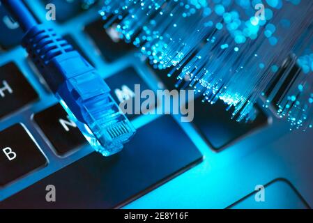 Internet cable, RJ-45 plug on laptop keyboard. High speed fiber optic internet concept Stock Photo