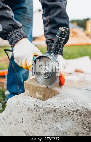 Master tiler cuts concrete paving stones with a circular saw - diamond disc for stone Stock Photo
