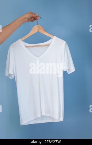 hand holding a white empty cloth on a shoulder, blue background Stock Photo