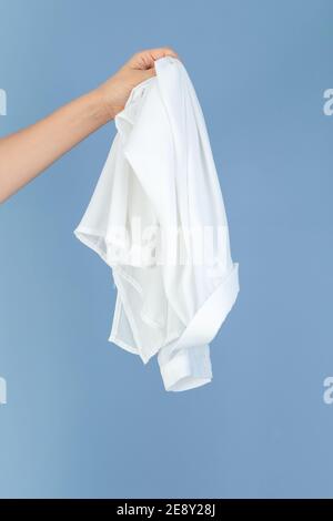 hand holding a white silk textile, blue background empty space for text Stock Photo