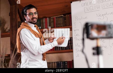 Indian Male Teacher Making Video Lecture Standing Near Blackboard Indoors Stock Photo