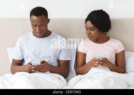 Young black woman eavesdropping on her boyfriend using mobile phone Stock Photo