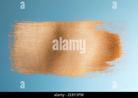 Golden paint brush stroke on blue paper Stock Photo