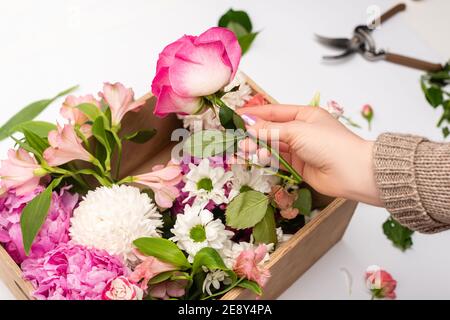 cropped view of woman holding pink flowers near wooden box on white Stock Photo