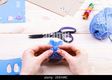 How to make a bunny from pom-poms for Easter decor. Children's art project. DIY concept. Hands make a blue Easter bunny out of a pompom. Step by step Stock Photo