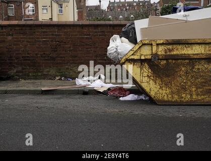 An overflowing skip with household waste littering pavements and roads with copy space Stock Photo