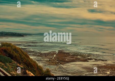 Beach Walkers in Encinitas California Surfers Beach Low Tide Sunny Day Cliffs and waves Stock Photo